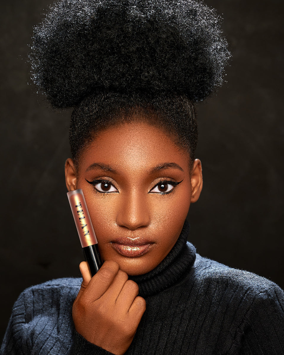 A model holding Telan Nuru lip gloss against her face